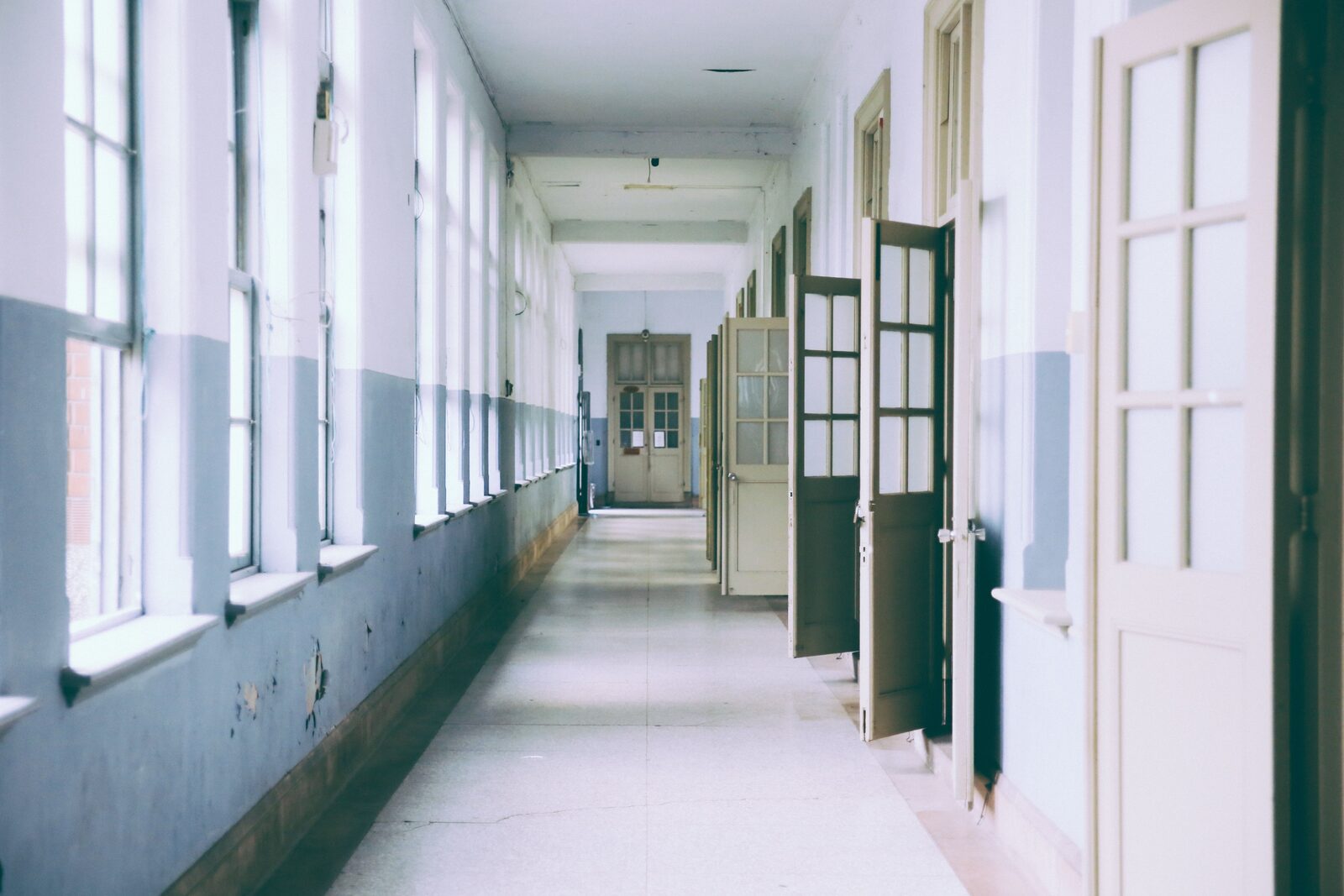 The old wing today: a worn institutional corridor lined with tall windows and doors